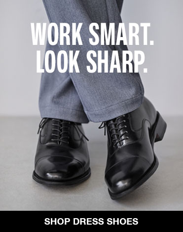 Crossed feet wearing a pair of classic black men's dress shoes with grey slacks on. The image reads